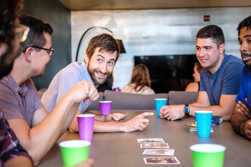 Men laughing over conversation cards at a Dinner Group