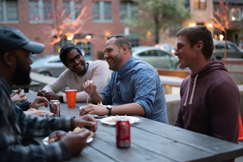 Men talking around an outdoor table