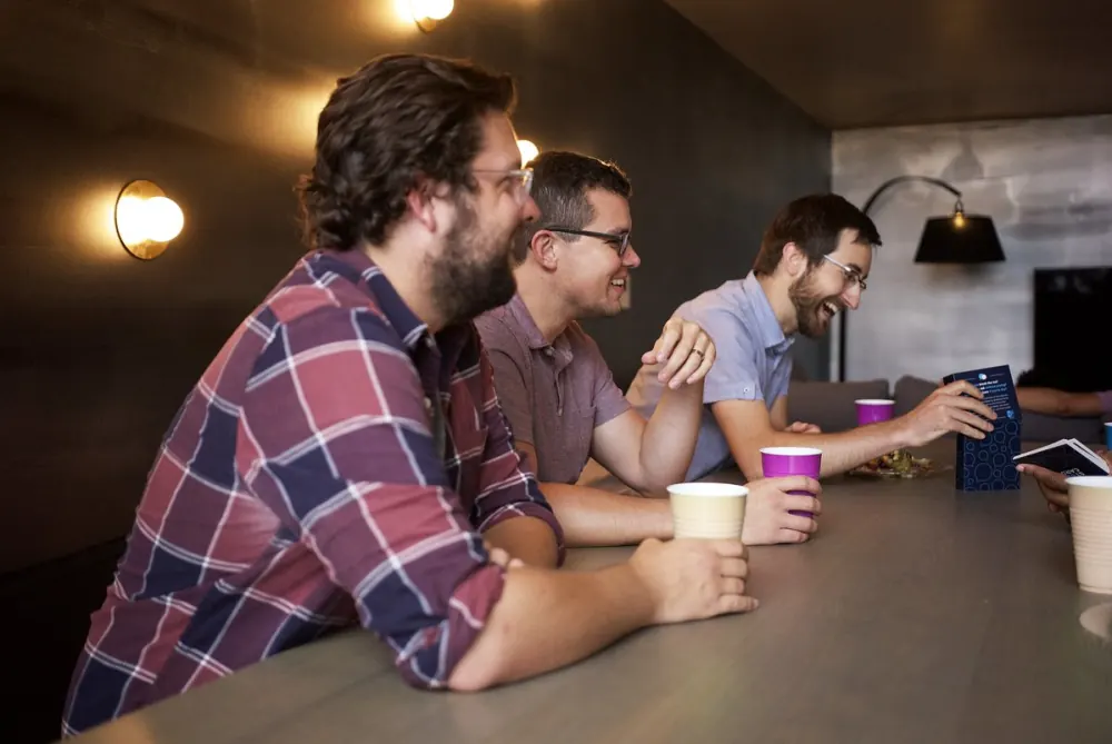 Three men laughing together around a table