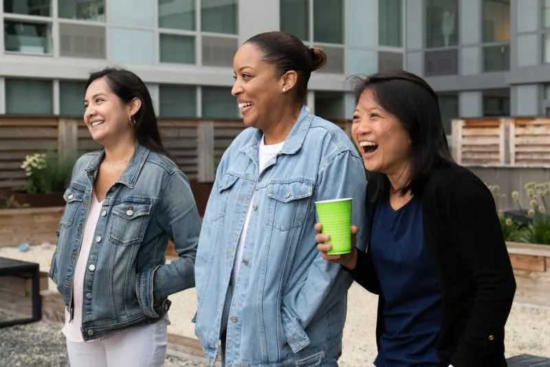 Three women laughing together outside