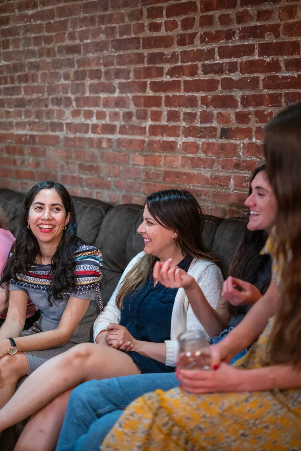 Three women laughing together on a couch