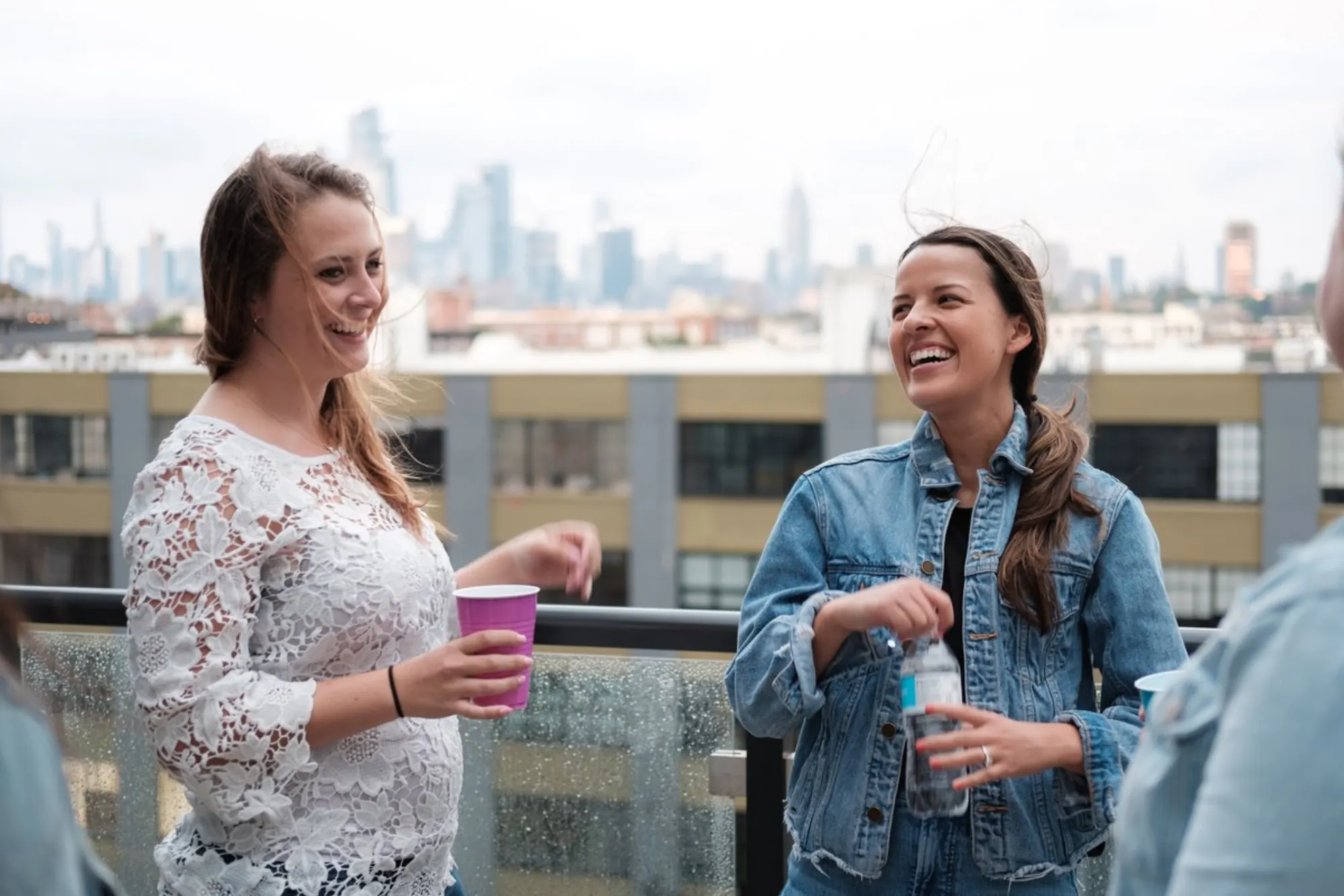 Two women laughing on a Hoboken rooftop